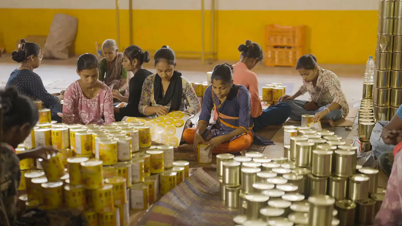 Workers labelling mango pulp cans