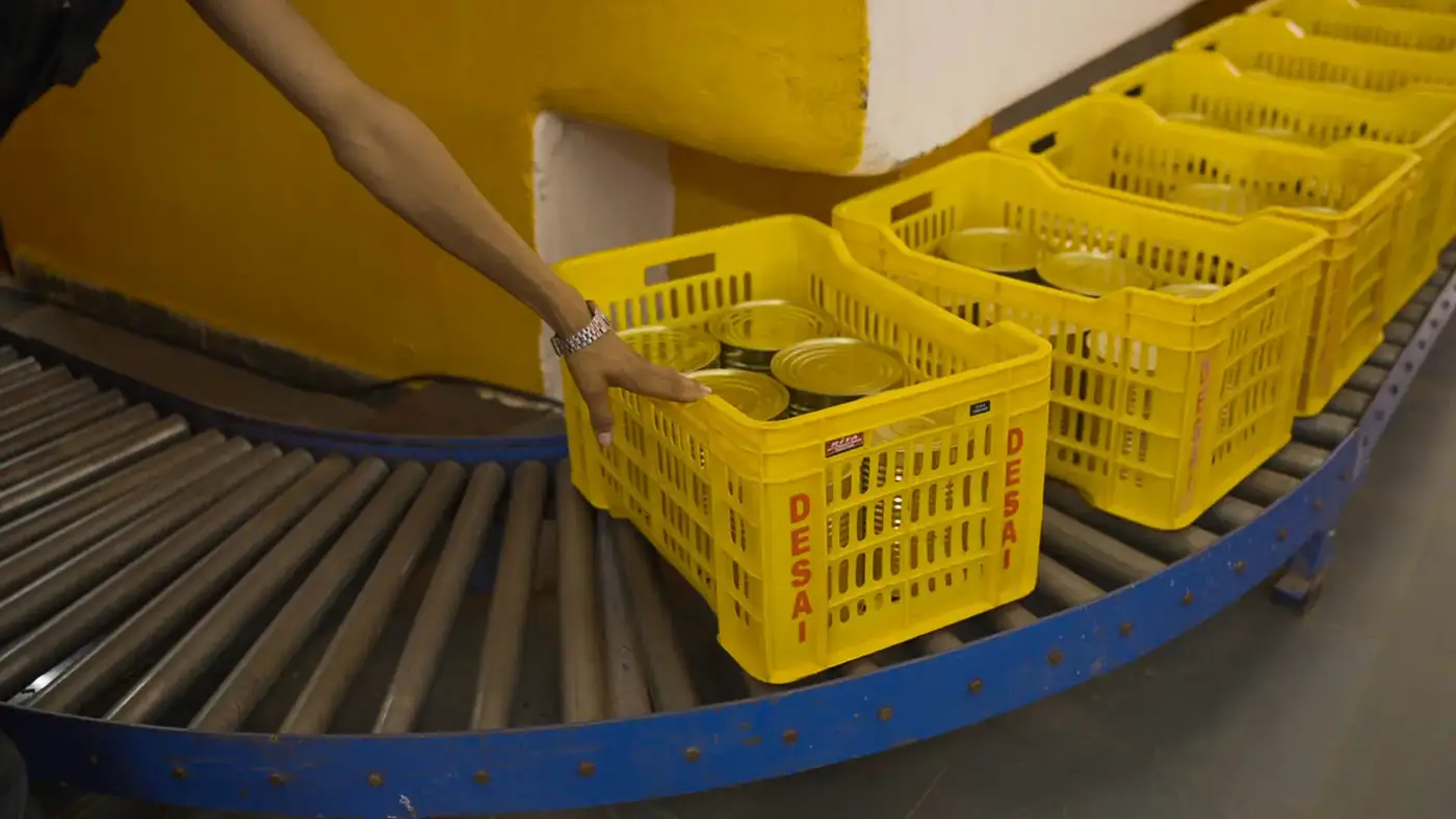 Cans in Desai crate on roller conveyor